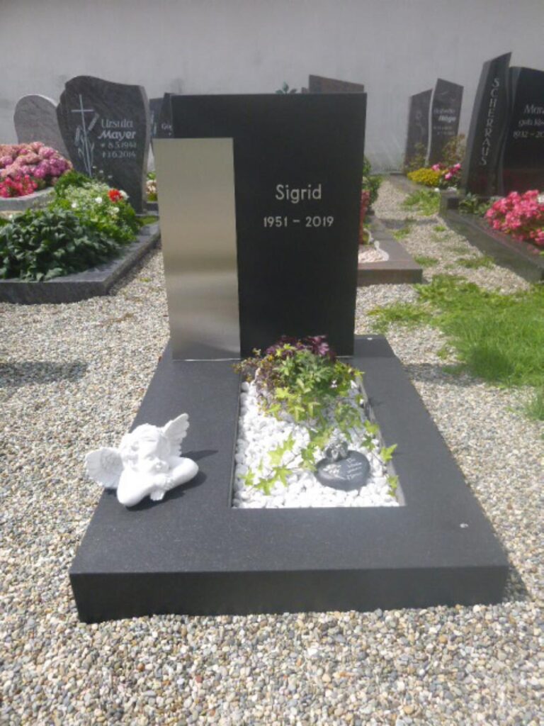 Grabstein für Sigrid (1951-2019) mit Engel. Grabsteine im Hintergrund. Steinmetz Meisterbetrieb