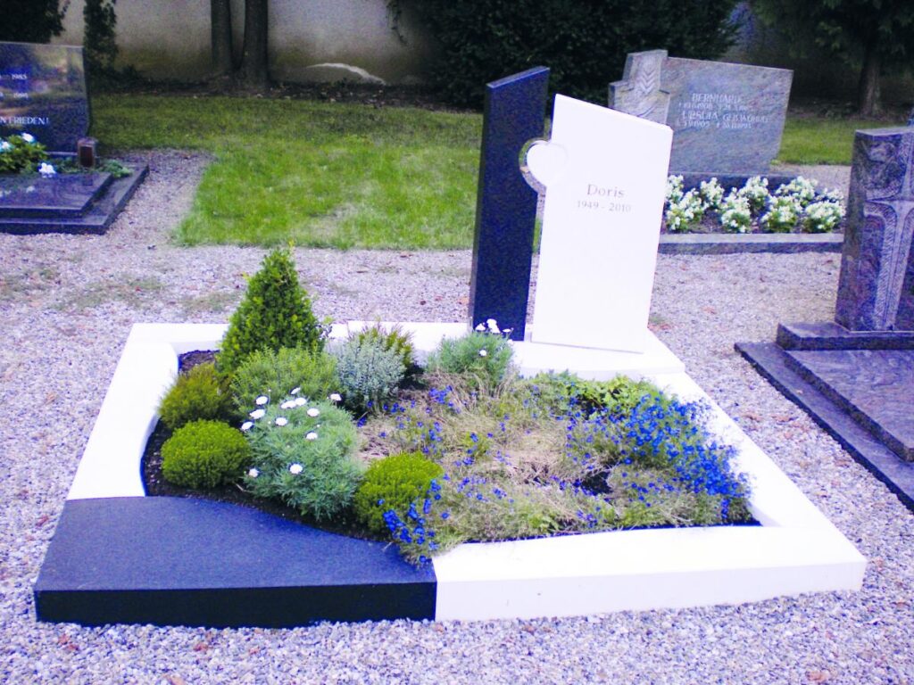 Grabstein: Modernes Grab mit blauen Blumen und der Inschrift "Doris 1949-2010". Steinmetz Meisterbetrieb