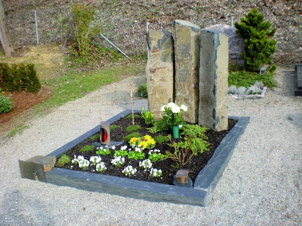 Moderne Grabsteine mit Blumen und Pflanzen auf einem gepflegten Grab. Steinmetz Meisterbetrieb