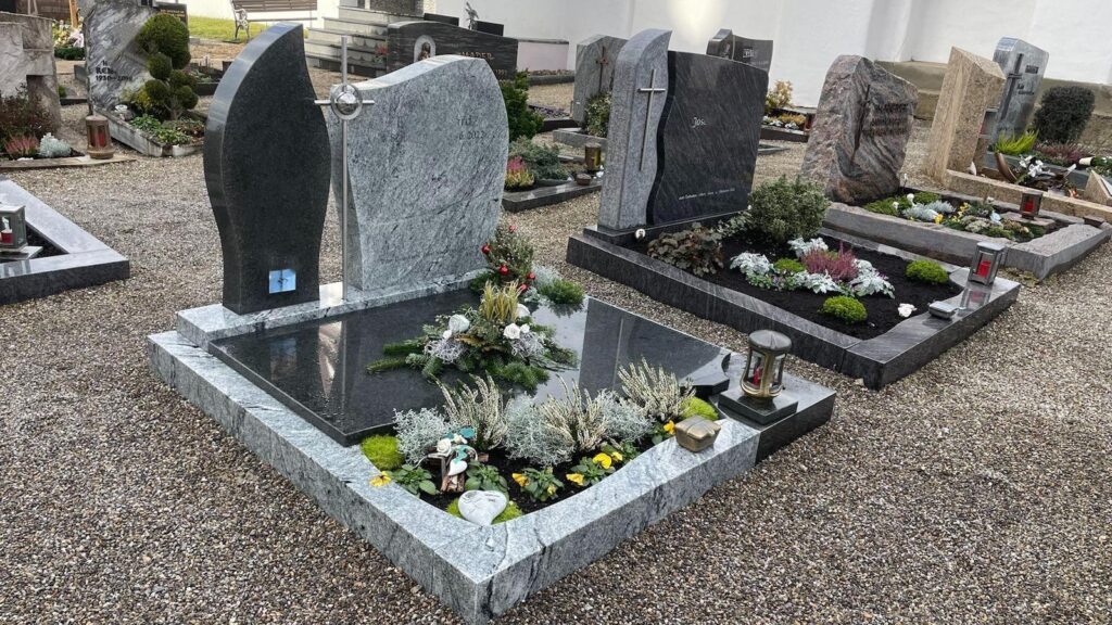 Moderne Grabsteine auf einem Friedhof, geschmückt mit Pflanzen und Dekorationen. Steinmetz Meisterbetrieb