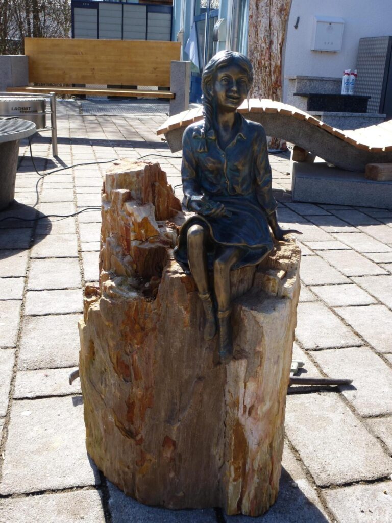 Bronzestatue einer sitzenden Frau auf einem Baumstumpf. Meisterbetrieb-Element. Steinmetz Meisterbetrieb